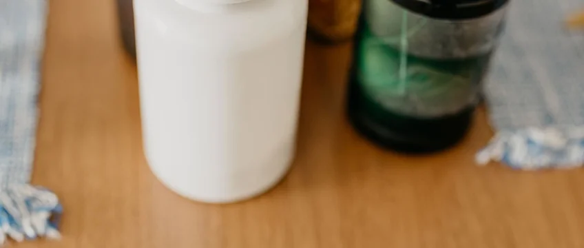 Probiotic and vitamin supplement bottles with capsules on a wooden surface