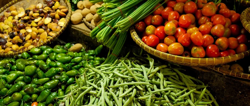 Fresh green beans, tomatoes and other vegetables displayed in baskets at a market