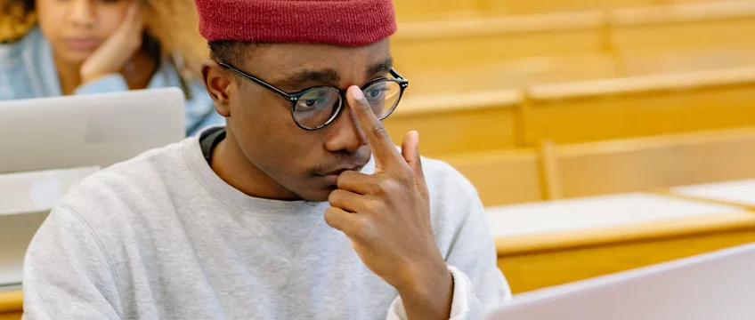 Students in a university lecture hall studying with laptops and notebooks