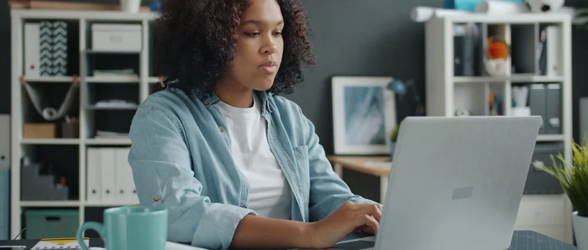 Young woman working remotely on a laptop at a desk in a home office