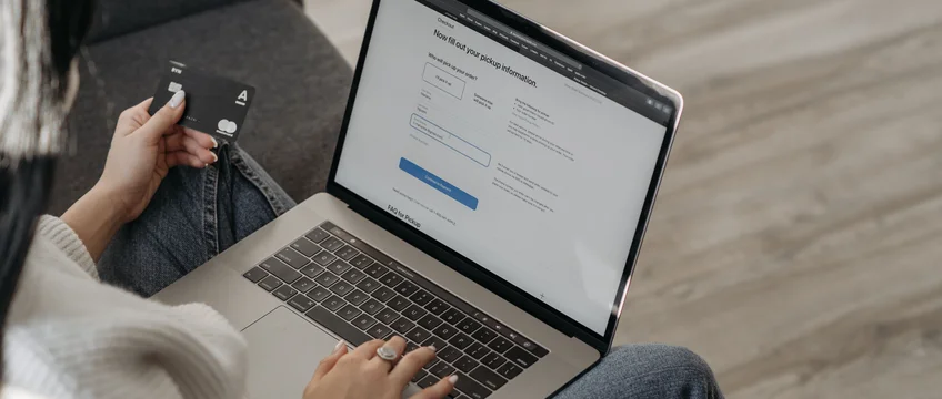 Person checking a checkout page on a laptop while holding a credit card